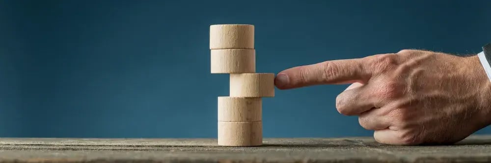 finger pushing a wooden tower into alignment