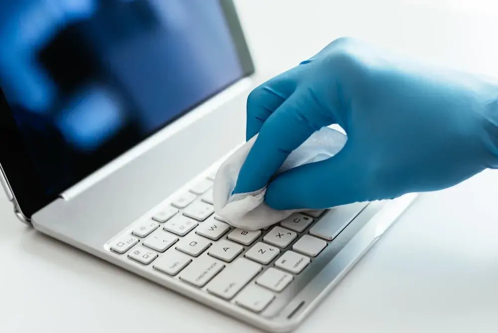 hand wiping down keyboard