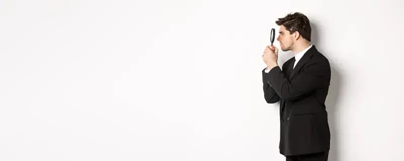 man in a suit searching with a magnifying glass