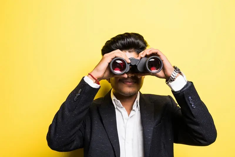 man in suit using binoculars